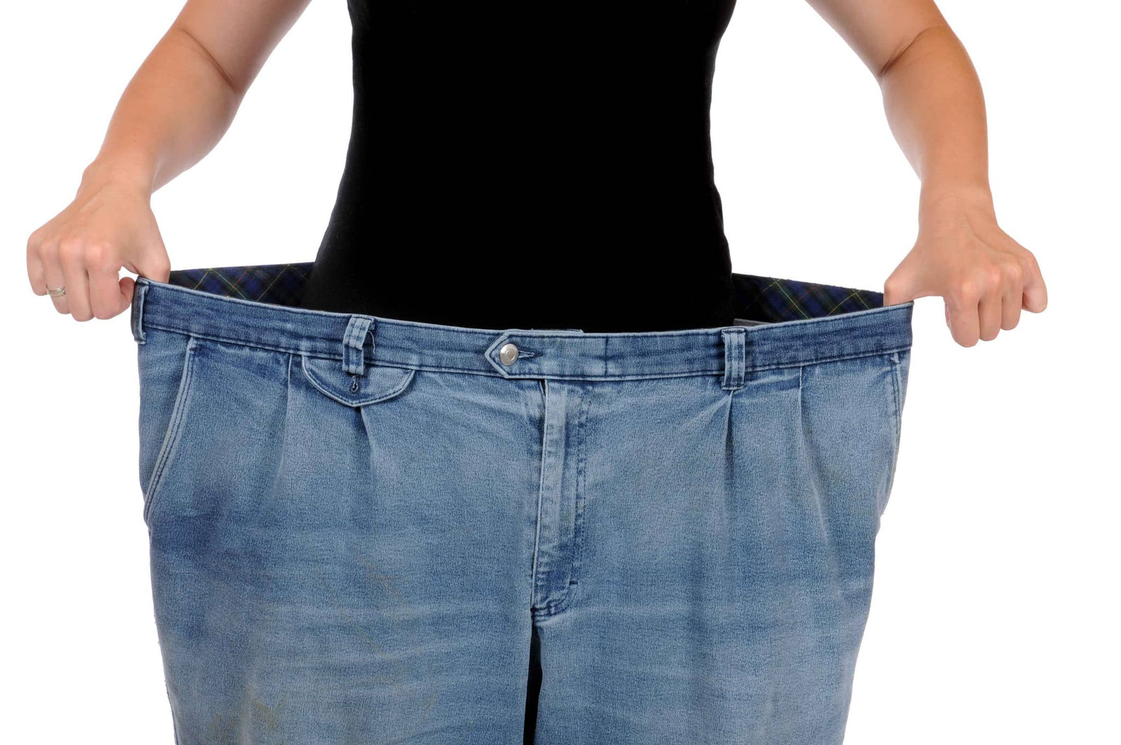 Person hält zu große blaue Jeanshose vor dem Körper für Gewichtsverlust und Abnehmen