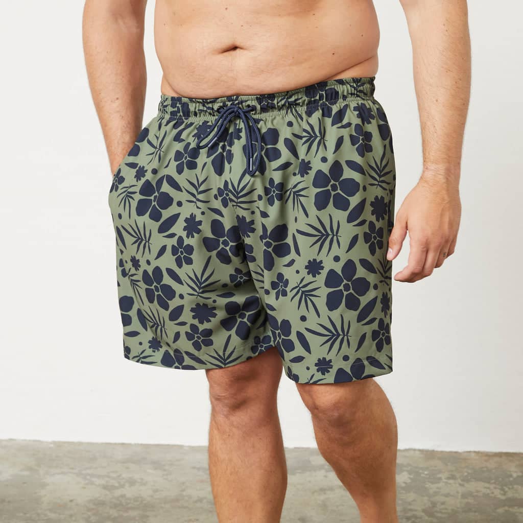 Herrenmodel trägt grüne Badeshorts mit Blumenmuster aus der Kollektion Badetextilien Übergröße Herren
