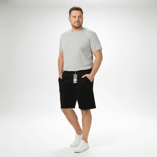 Mann trägt schwarze Bermuda von Ahorn Sport mit grauem T-Shirt und weißen Sneakers