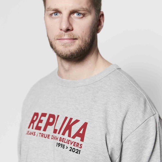 Herrenmodell trägt graues Sweatshirt Übergröße Herren mit rotem REPLIKA Schriftzug und Rundhalsausschnitt