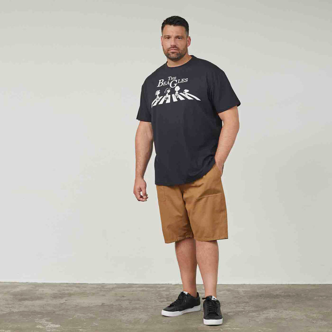 Mann trägt schwarzes T Shirt Peanuts Snoopy mit Beatles Print und braune kurze Hose